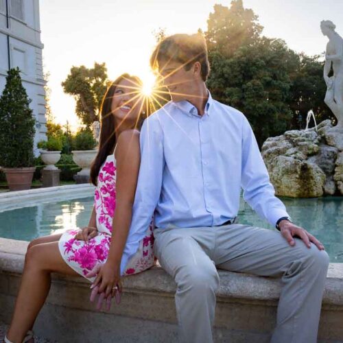 Sitting on the edge of a fountain and taking photos together during a lifestyle photo session with a professional photographer from Rome