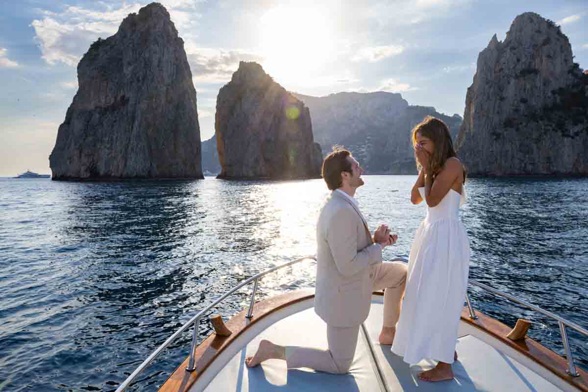 Knee down boat proposal in Capri photographer professionally by Andrea Matone photographer stranding on the vessel with the faraglioni rocks as perfect backdrop 