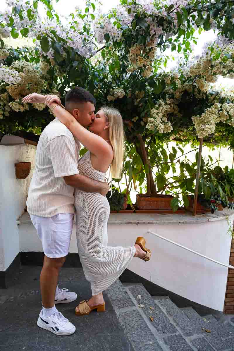 Romantic couple portrait surrounded by vibrant bougainvillea flowers during an intimate engagement photography session on Amalfi Coast