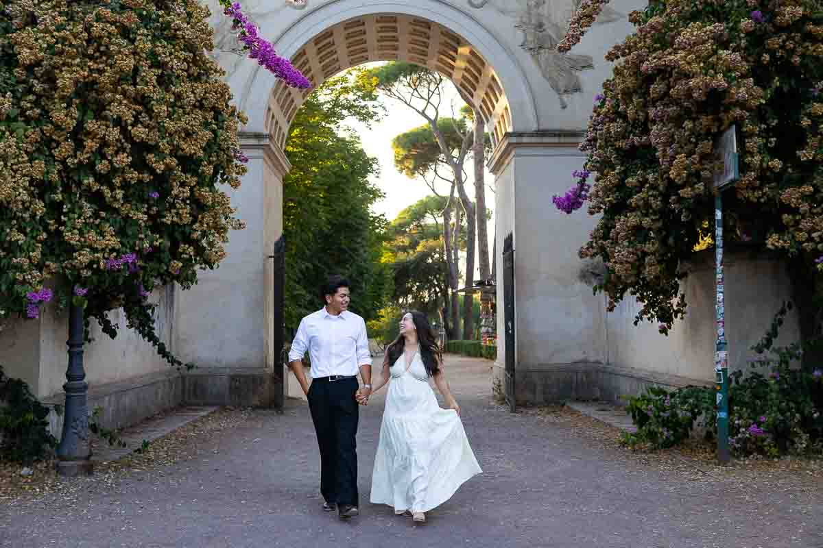 Walking in the park holding hands passing through the arch while being subject of lifestyle photography 