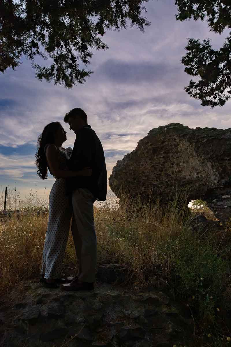 Artistic silhouette of two lovers against a colorful evening sky, with archaeological ruins creating a dramatic photographic backdrop