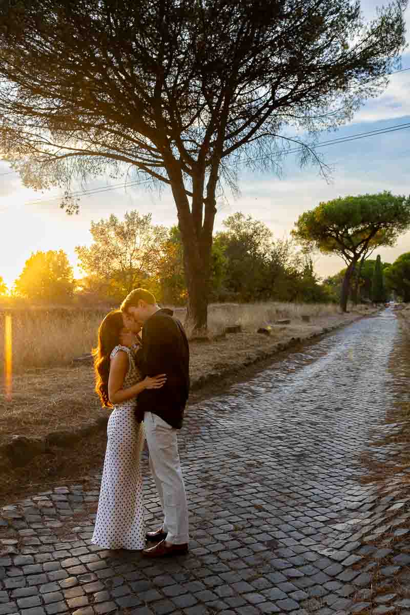 Newly engaged couple sharing a tender kiss beneath the warm colors of sunset during an intimate evening portrait session