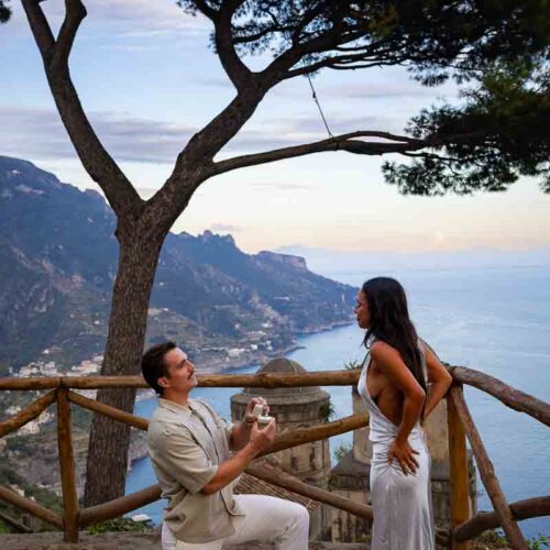 A surprise marriage proposal at Villa Rufolo during the blue hour, with the man kneeling against the iconic twin-domed Church of the Annunziata background