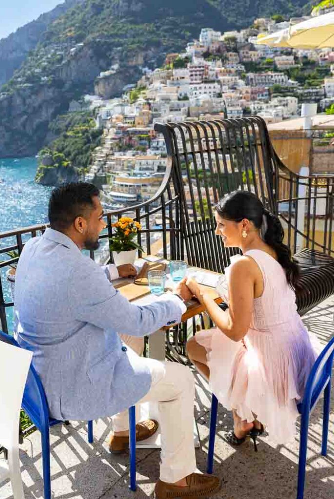 A couple enjoying an outdoor meal on a balcony overlooking the vertical hill scenery.