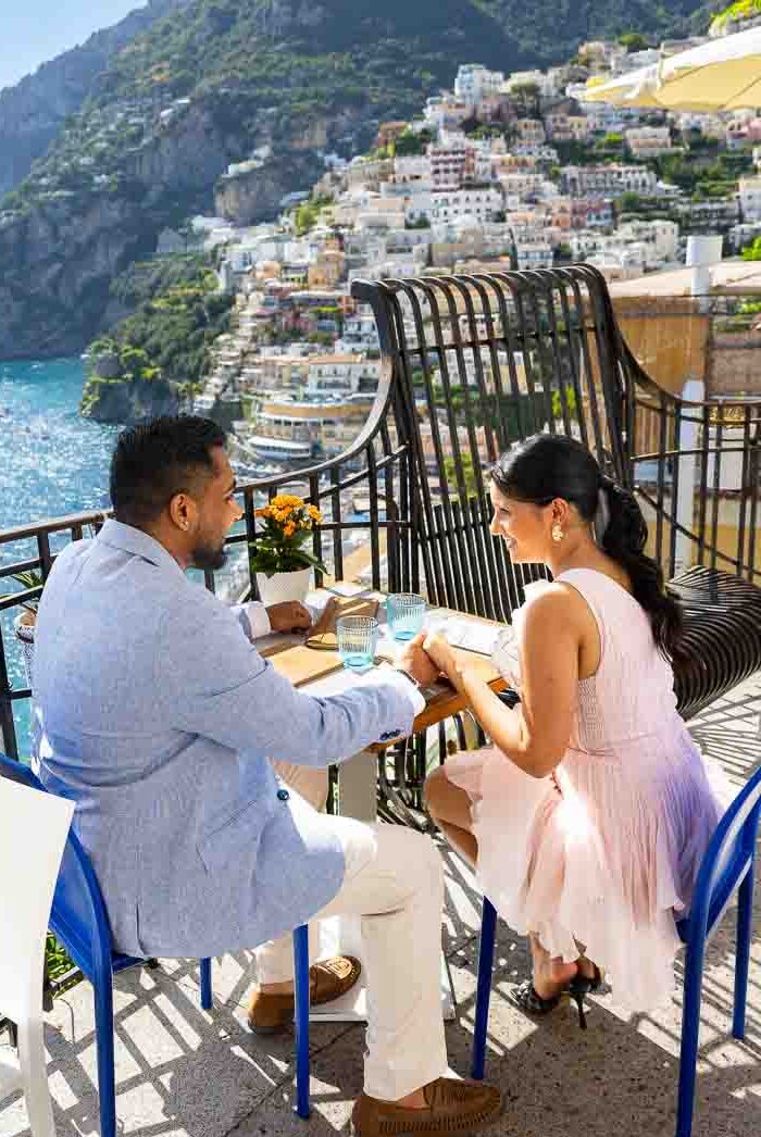 A couple enjoying an outdoor meal on a balcony overlooking the vertical hill scenery.