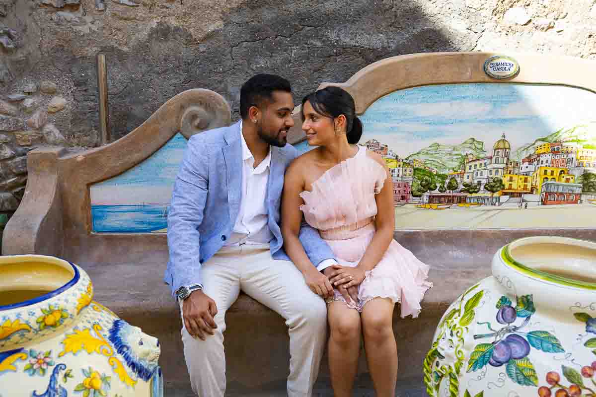 Candid moment showing two travelers relaxing among decorated Mediterranean ceramic pots.