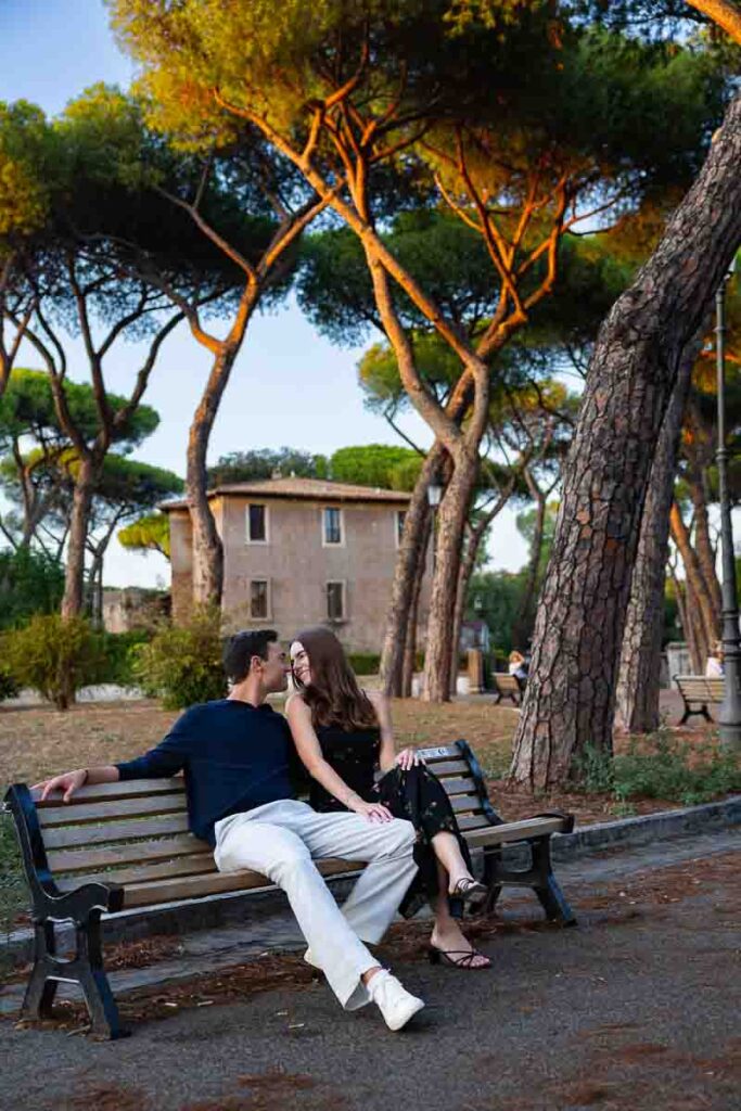 Romantic photo session of a couple sitting down on a wooden bench in park in Rome Italy