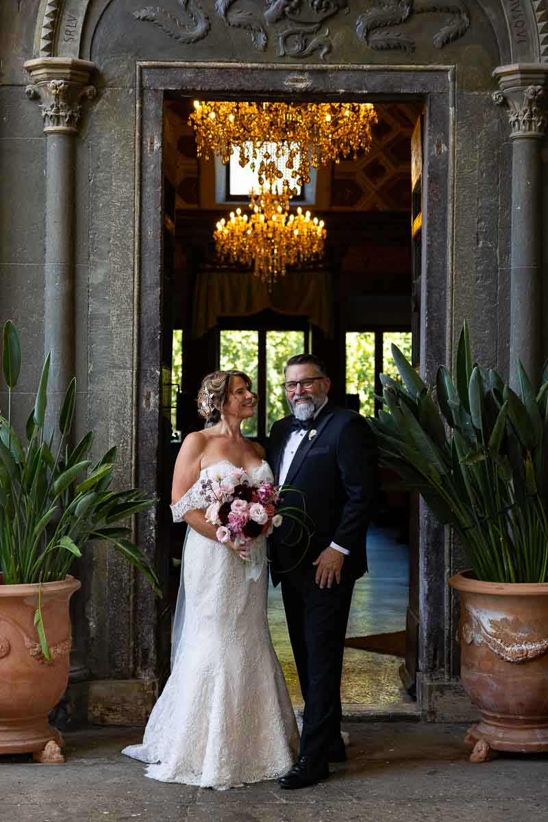 An elegant newlywed portrait framed by an ancient stone palace doorway.