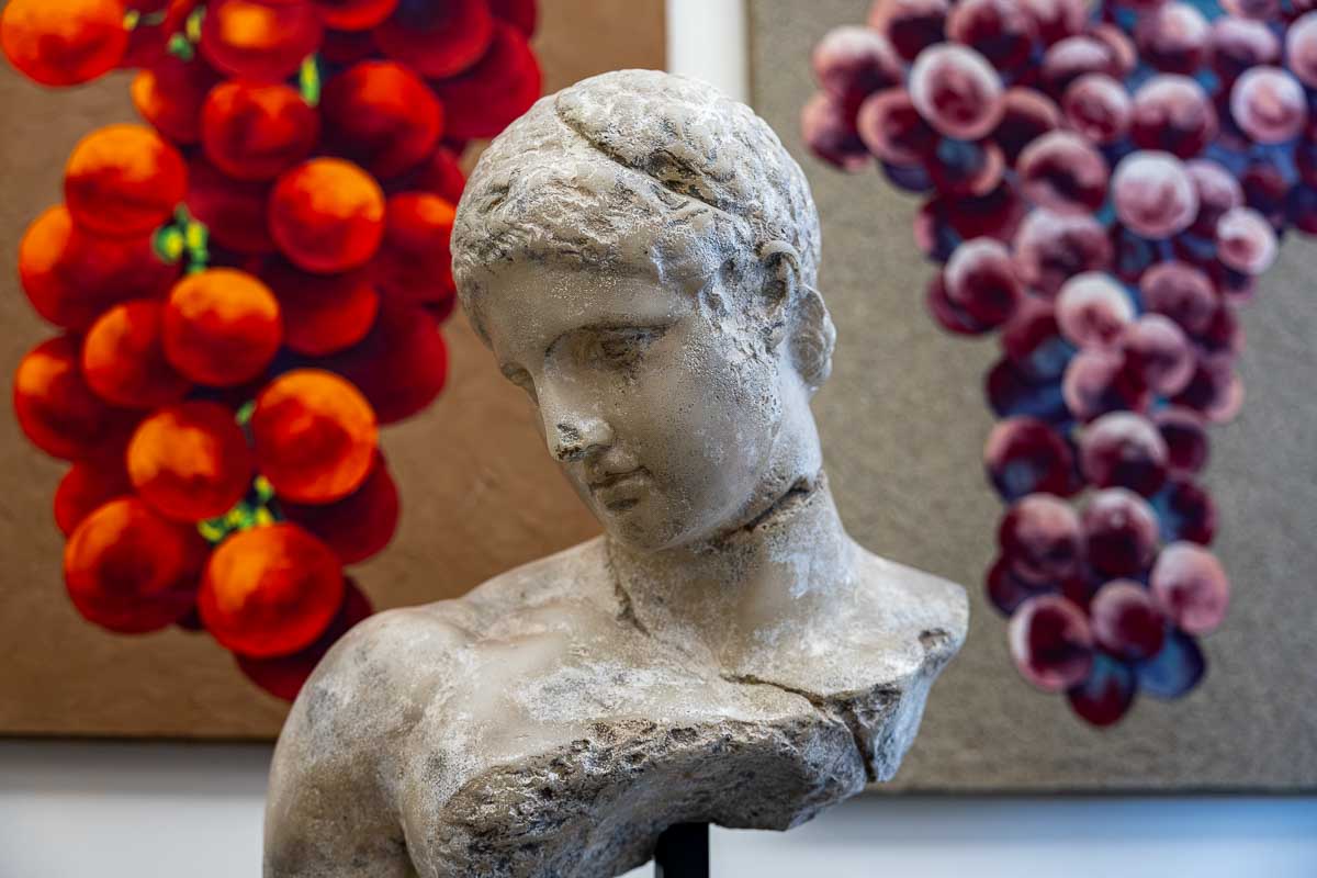 A classic Roman statue framed by colorful grapes on a rooftop in Piazza Navona.