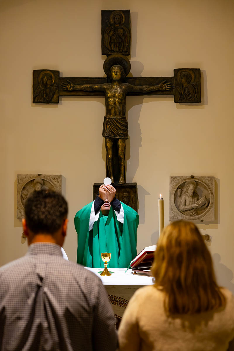 Candid documentation of a sacred ritual gesture performed by the vestment-clad clergy over the couple renewing promises