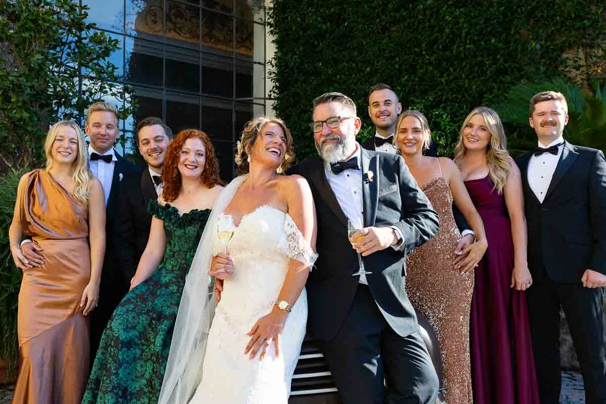 A joyful group portrait of the entire wedding party celebrating on the estate grounds.