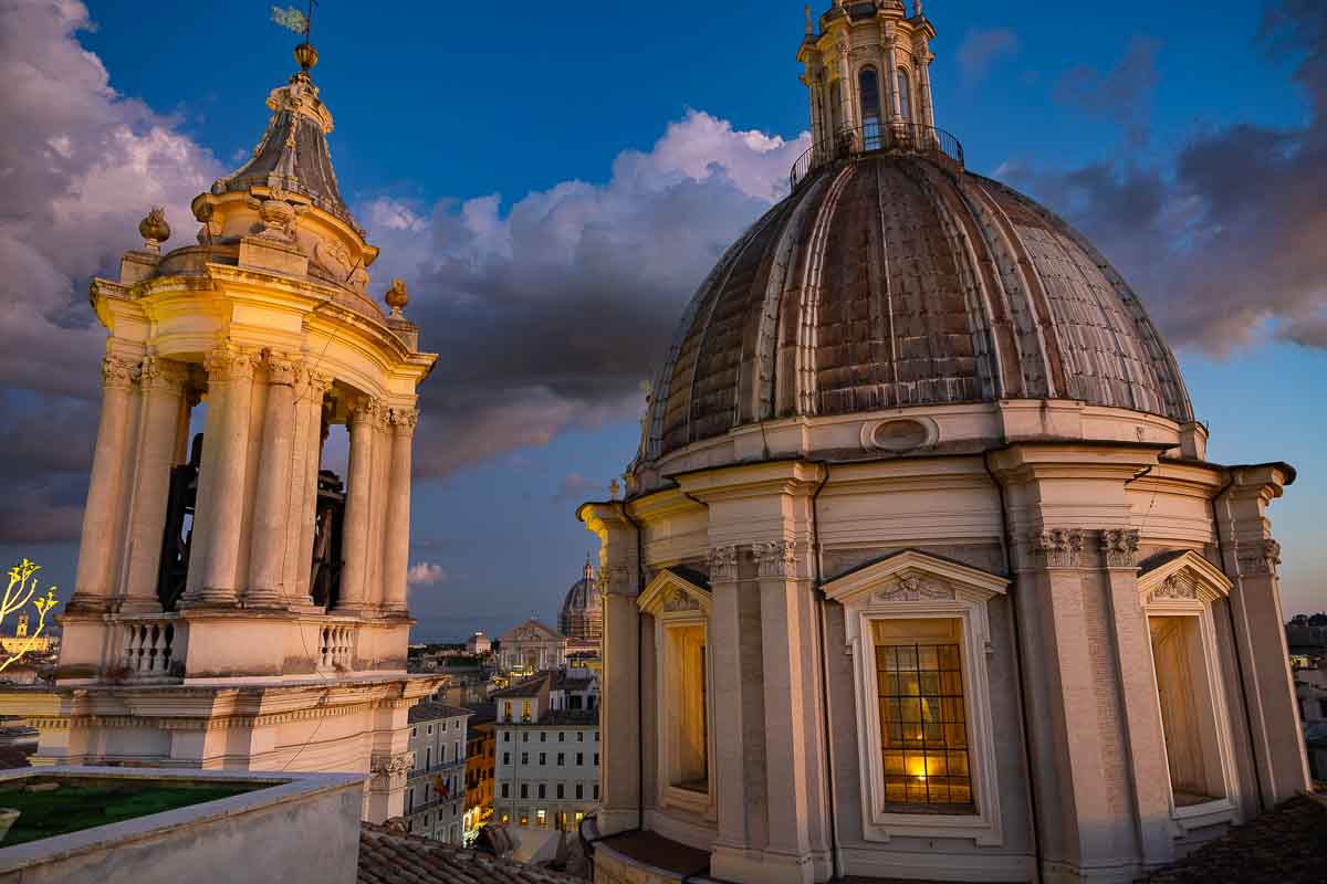 The iconic S. Agnese domes designed by Borromini lit up against the deep blue hour sky.