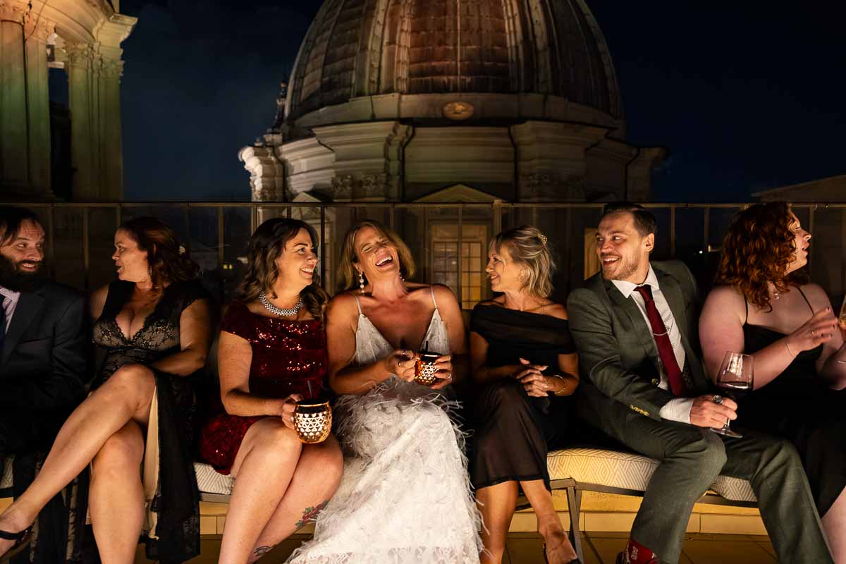 A group of guests sharing a fun laugh and talking together on the rooftop.