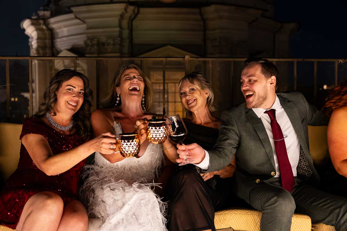 Happy guests toasting their drinks under the warm terrace lighting.