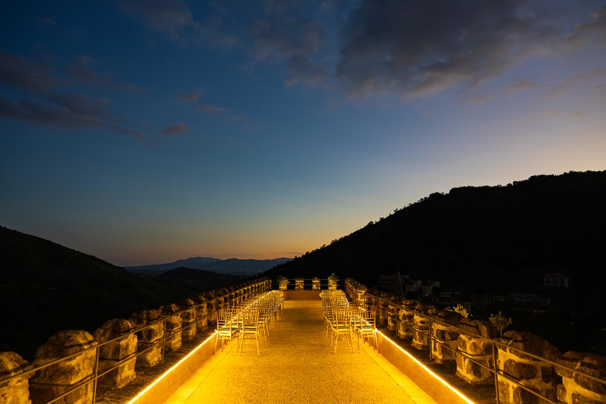 A scenic dusk perspective looking out across the illuminated grounds and misty valley.