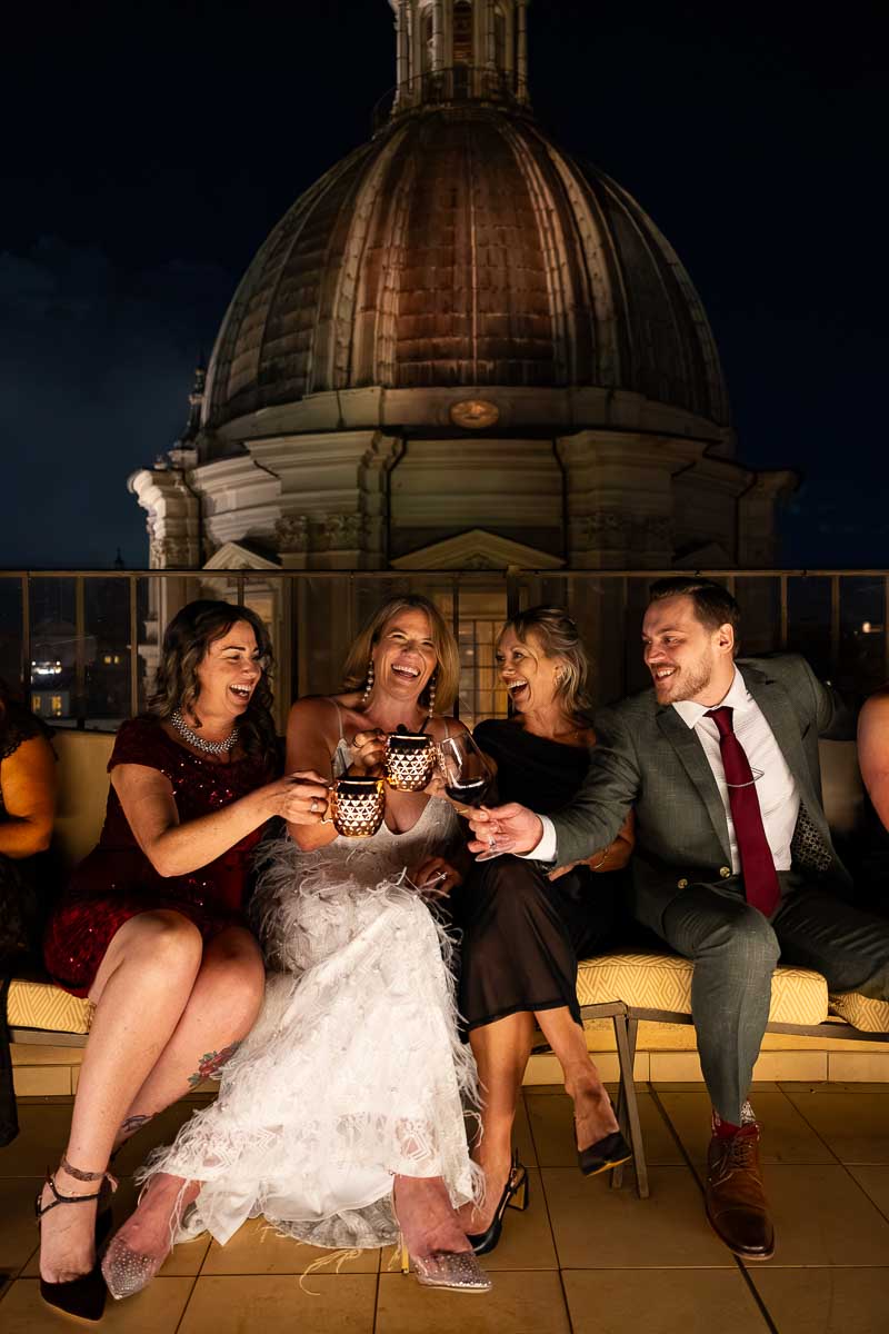 A vertical framing shot of friends toasting their glasses against the evening sky.