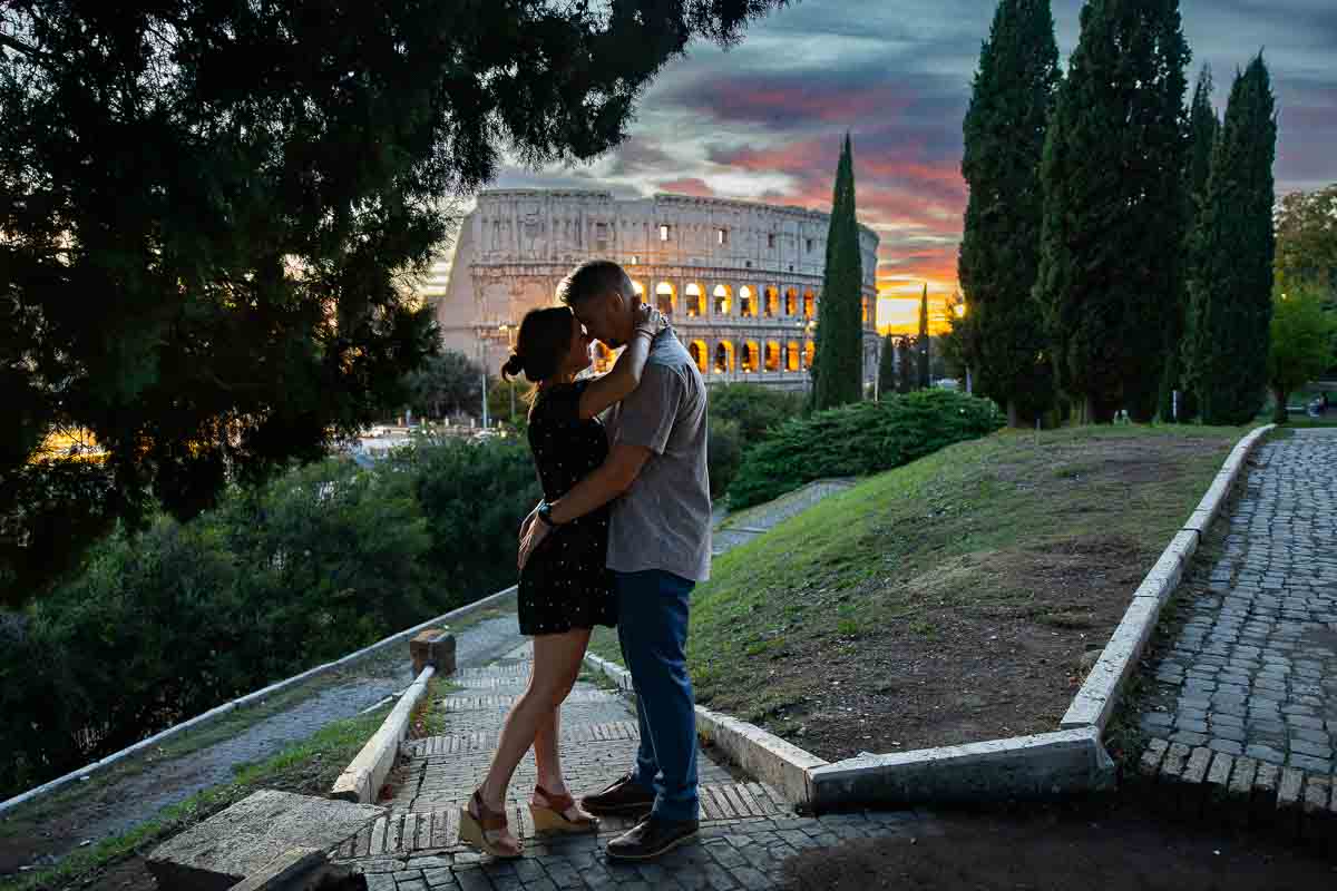 An intimate couple embrace during a twilight session against the illuminated arches of the Roman landmark.