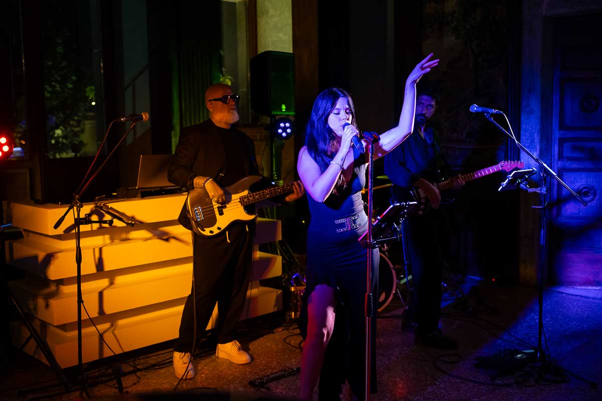 Singer nighttime photographer taking pictures of her as she sings from the sides